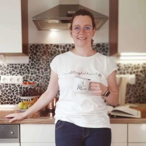 Frau mit Kaffeetasse vor Küchenzeile mit weißem T-Shirt