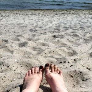 Füße im Sand und im Hintergrund die Ostsee