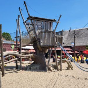 Holzspielturm auf Spielplatz mit Sand