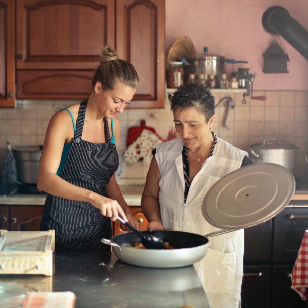 Zwei Frauen in der Küche schauen in Kochtopf