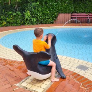 Kind auf Plastik-Seehund am Schwimmbeckenrand