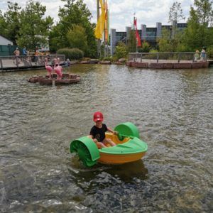 Kind im grünen Ruderboot auf Teich