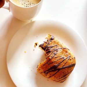Angebissenes Schoko-Croissant auf einem weißen Teller