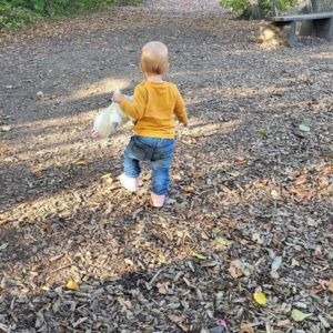 Kleinkind mit gelbem Oberteil und Jeans auf Spielplatz