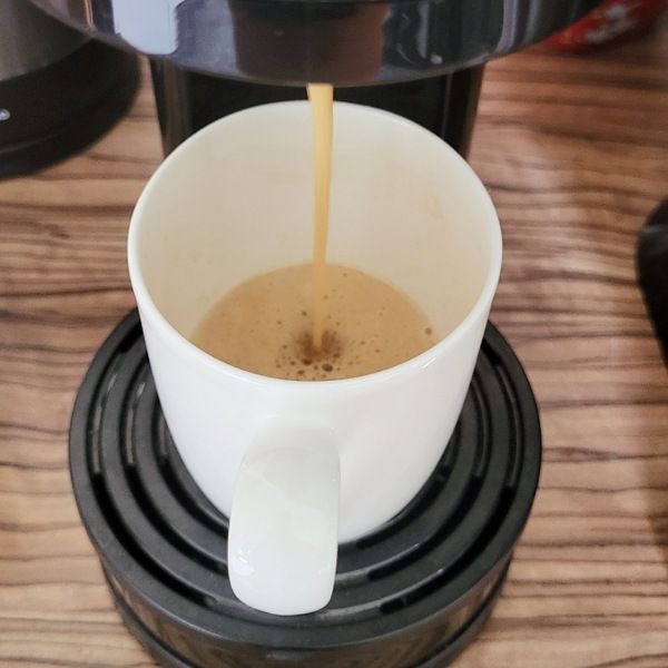 Weiße Kaffeetasse in Senseo Maschine und Kaffee läuft rein