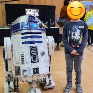 Kind steht neben Modell von R2-D2