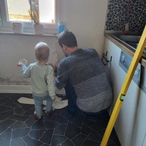 Kind und Mann reißen Tapete von der Wand