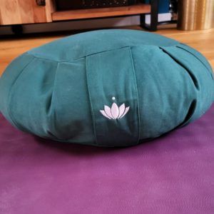 Grünes Meditationskissen auf lila Yoga-Matte
