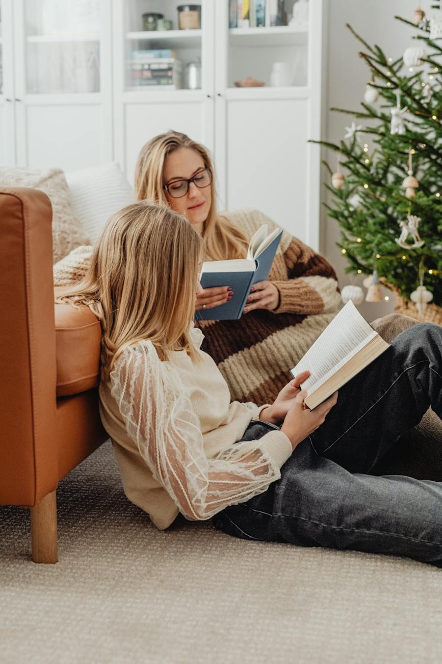 mother and daughter reading books in a living room at christmas