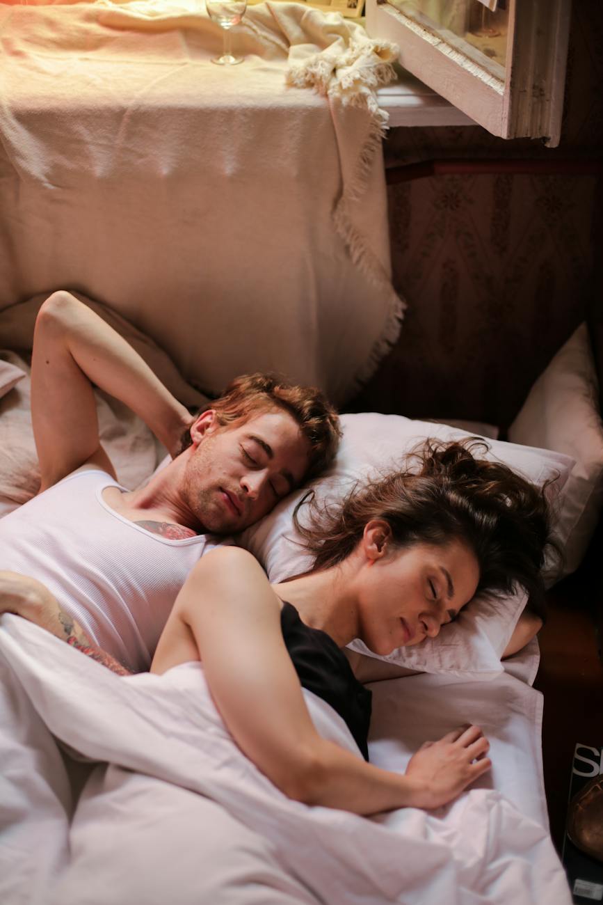 Frau und Mann liegen im Bett mit weißer Bettwäsche und schlafen erholsam
